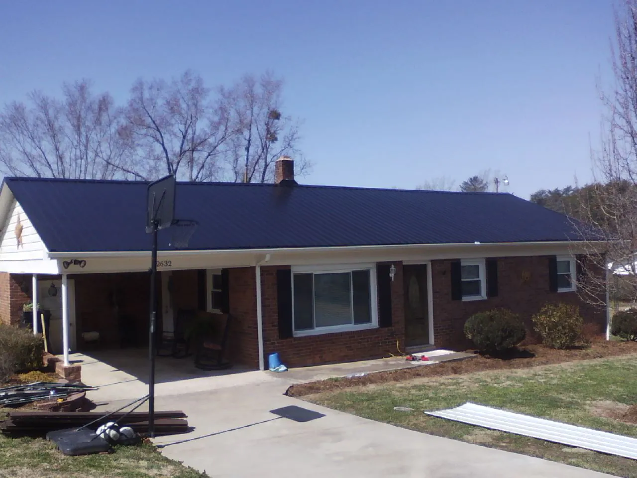 Finished dark blue metal roof on a brick ranch with a carport in Midlothian
