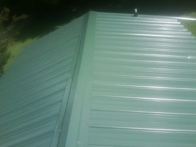New green metal panels meeting at the ridge of a roof — Flat Roof Repair work by our crew in Midlothian
