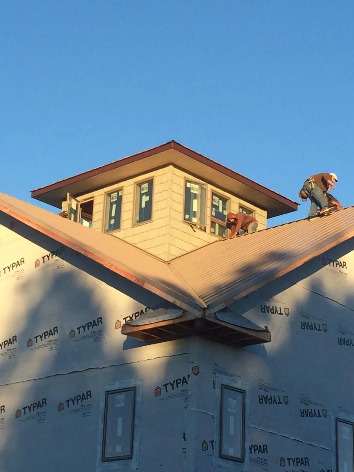 Roofers working around a rooftop cupola on a new metal roof at sunset — Roof Waterproofing in Midlothian by Roofing Brothers